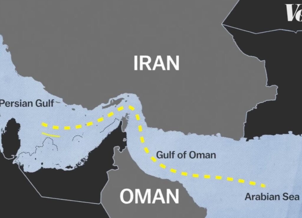 A map of the Strait of Hormuz showing the maritime border between Iran and Oman, with a yellow dashed line indicating the primary shipping lane connecting the Persian Gulf to the Gulf of Oman and the Arabian Sea.