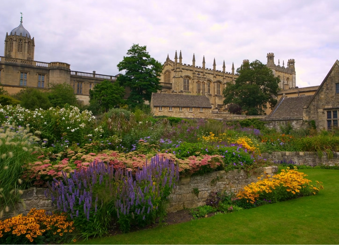 Historic Oxford college buildings overlooking colourful landscaped gardens in Oxford, England.