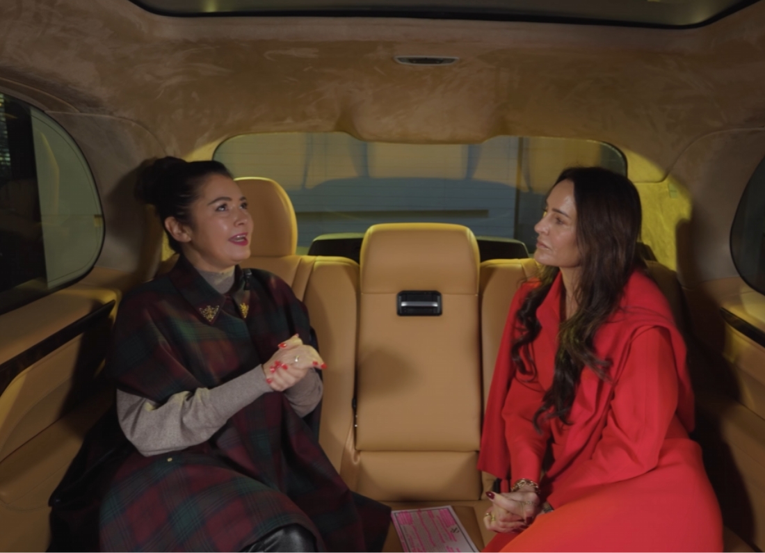 Laure Ferrari speaks during an interview inside a car while another woman listens.