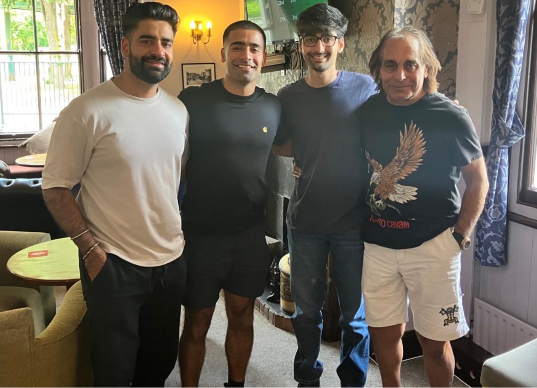 Four men standing together inside a pub or lounge area as part of a fundraiser campaign to help pay for brain cancer immunotherapy treatment for their father.
