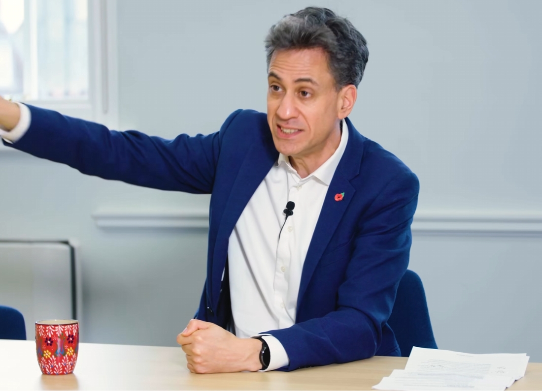 Energy Secretary Ed Miliband speaks during an interview while gesturing across a table.