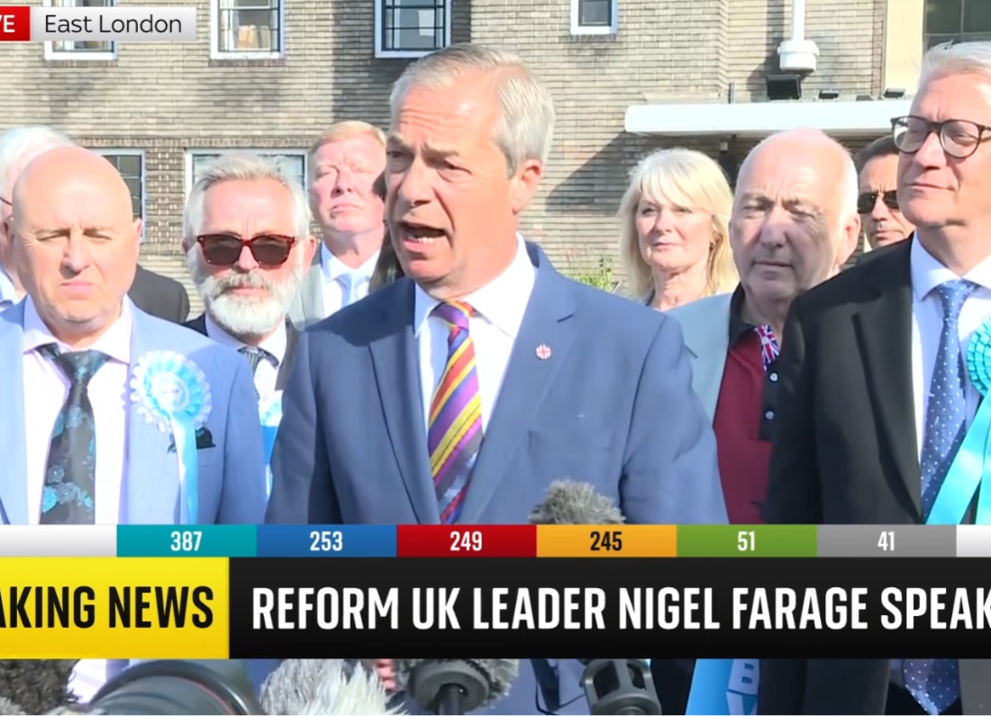 Nigel Farage speaks to the media surrounded by Reform UK supporters during election coverage in East London.