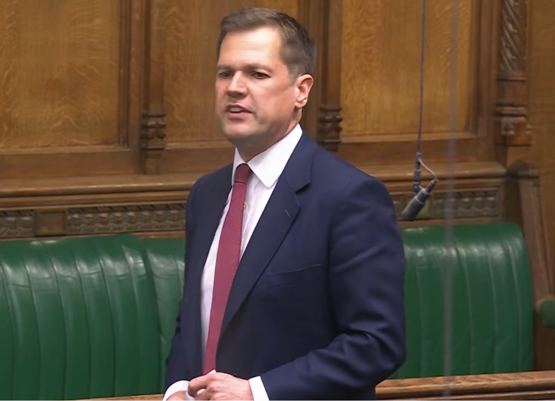 Reform UK MP Robert Jenrick speaking during a House of Commons debate while standing beside the green benches in Parliament.