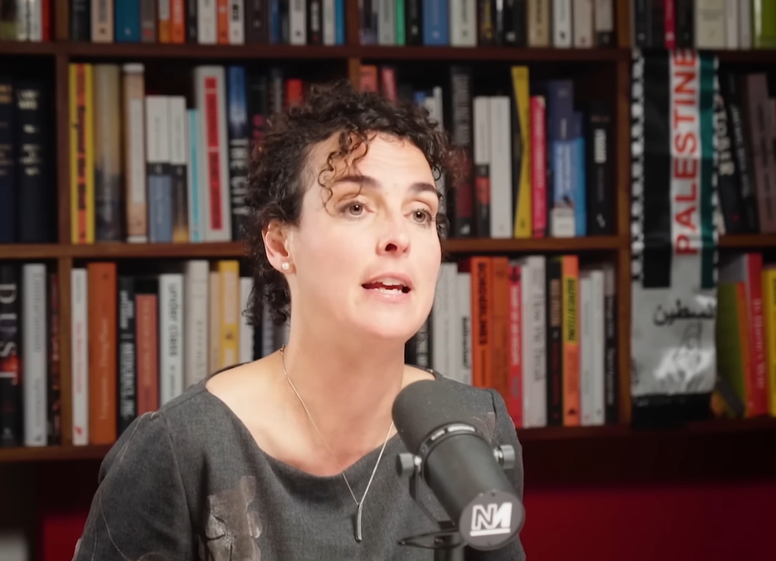 Economist Clara Mattei speaking into a microphone during an interview on Aaron Bastani’s Downstream podcast.