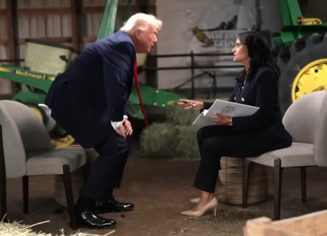 Donald Trump leans forward while speaking to NBC journalist Kristen Welker during a televised interview recorded in a barn-like setting with agricultural equipment visible in the background.