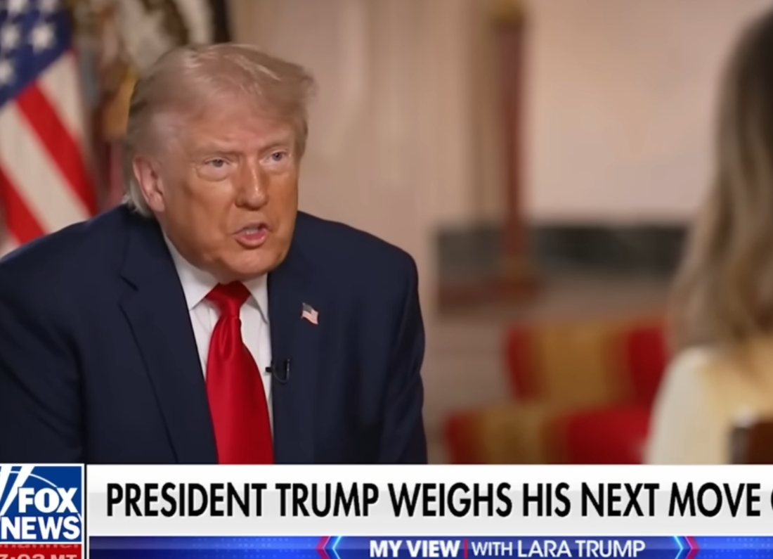Donald Trump speaks during a televised interview on Fox News, seated opposite an interviewer. He is wearing a dark suit, white shirt and red tie, with a blurred studio background and Fox News graphics visible on screen.