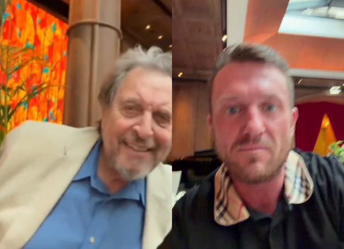 Split-screen image showing Tommy Robinson speaking via video call with Errol Musk in what appears to be a hotel or restaurant setting.