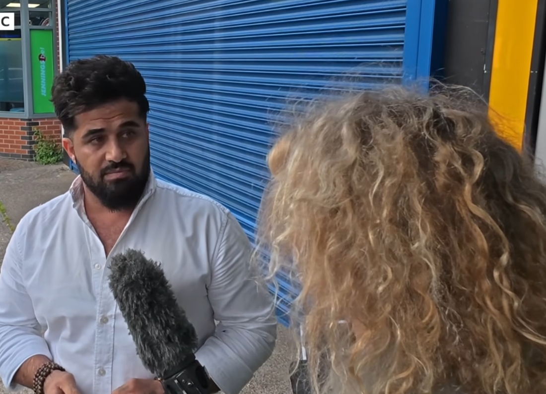 Convicted people smuggler Twana Jamal being confronted by a BBC reporter outside a building in the UK.