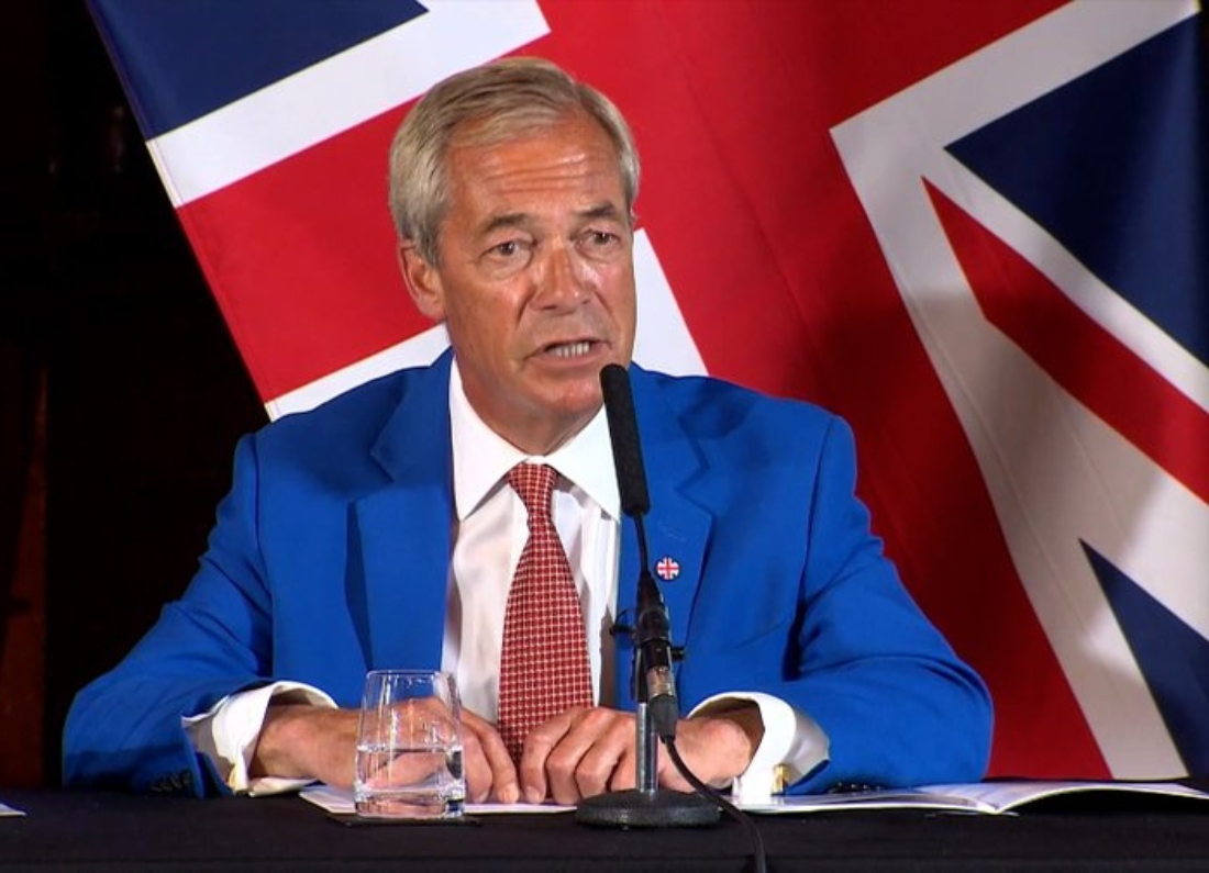 Nigel Farage speaking in front of Union Jack flags while announcing Reform UK’s Operation Fortress small-boats plan.